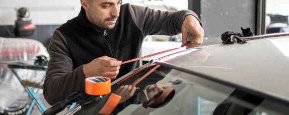 A man working on car windshield