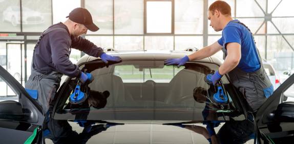 two workers replacing car windshield